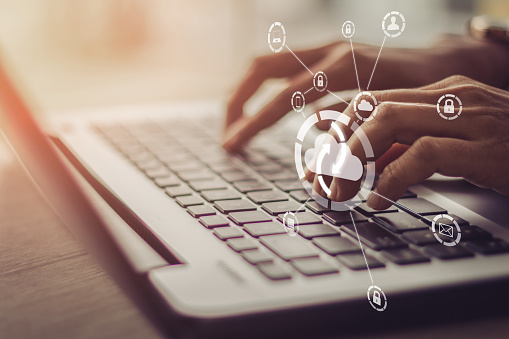 Young businesswoman working on his laptop in the office, select the icon cloud on the virtual display.Concept digital technology and
cloud computing