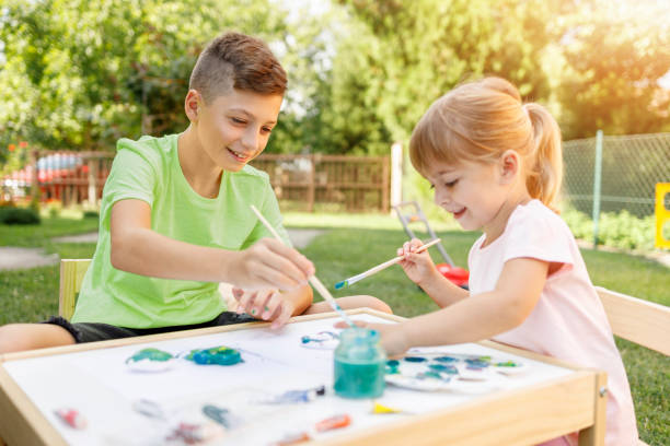 istock Cheerful siblings using watercolors outdoors 1312419412