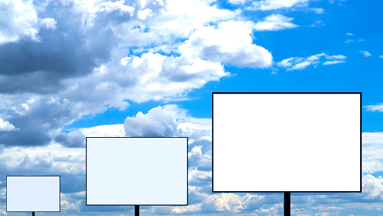 Three blank billboards stand in a row against a cloudy sky