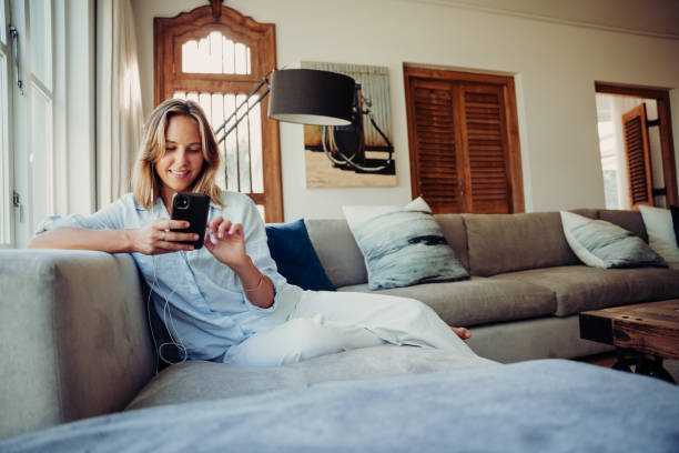 istock Caucasian female typing on cellular device relaxing on couch 1312422059
