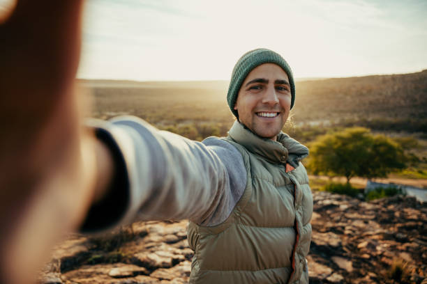 istock Caucasian young male taking selfie while camping in wilderness enjoying sunset 1312423319