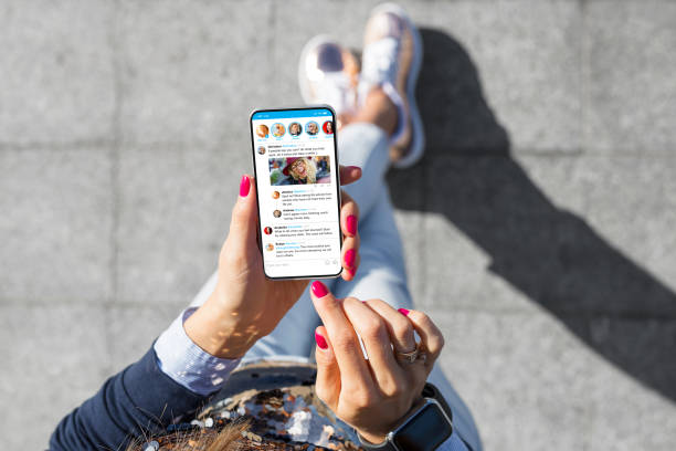 mujer usando aplicación de microblogging de redes sociales en su teléfono - compartir fotos fotografías e imágenes de stock