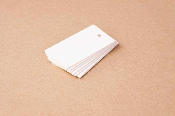 istock stack of white blank rectangular paper tag labels for clothing price tags on beige brown cardboard background, isolated 1312426318
