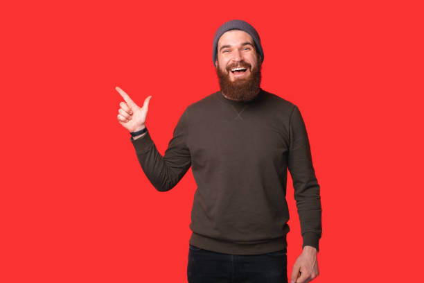 istock Portrait of handsome cheerful bearded man pointing away at copyspace 1312426433