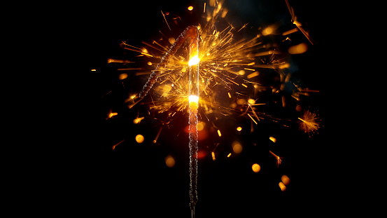 Close-up of sparkler in shape of 'NUMBER 1' emitting sparks while burning against black background.