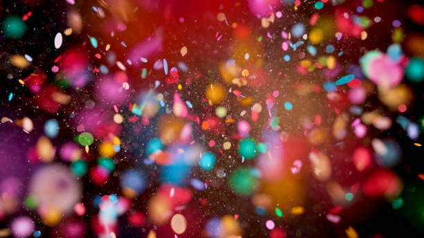 Close-up of confetti Close-up of multi coloured confetti flying mid-air against black background. celebrate stock pictures, royalty-free photos & images