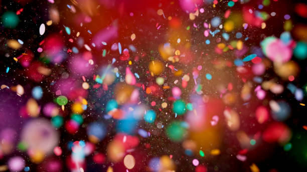 Close-up of confetti Close-up of multi coloured confetti flying mid-air against black background. variegated stock pictures, royalty-free photos & images