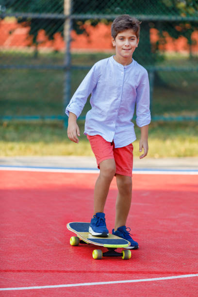 istock Young Boy is Enjoying a Long Board and Riding Through the Park. 1312429125