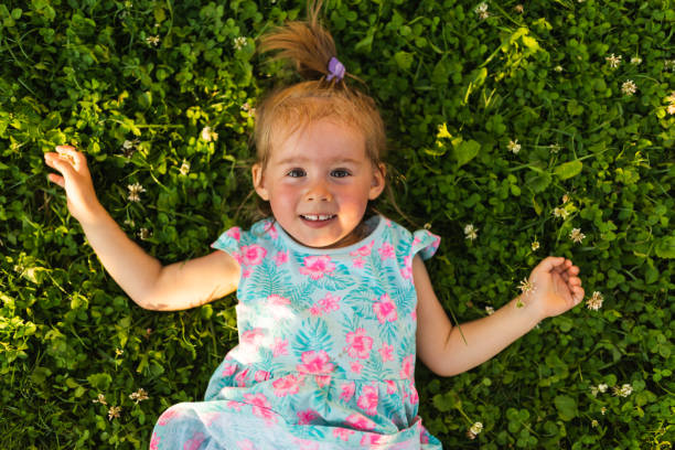 istock Young girl lying on grass laughing and looking up. 1312429153