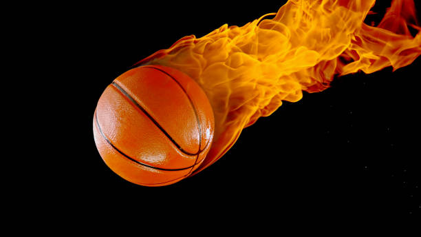 Close up image of professional basketball player about to do slam dunk fireball during basketball game in floodlight