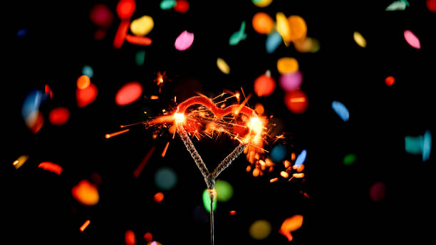 istock Close-up of heart shaped sparkler emitting sparks while confetti falling in background 1312431387