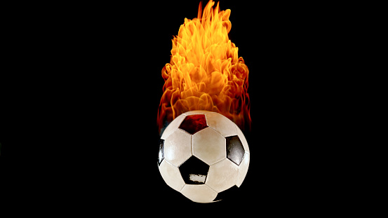 Close-up of burning football against black background.