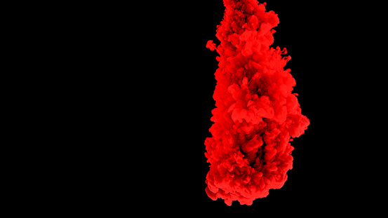 Close-up of red colour ink drop falling into water against black background.