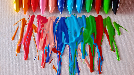 Close-up of crayons melting and dripping on white paper.