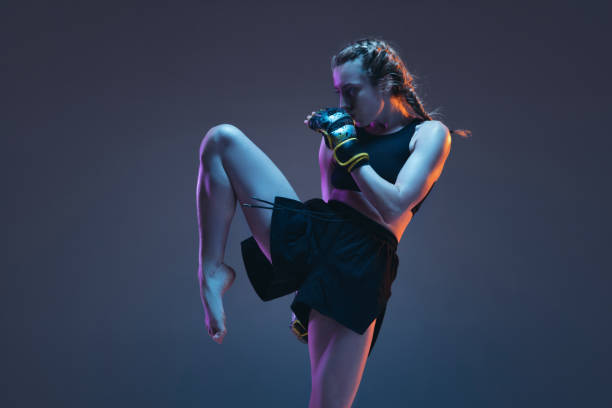 caucasian female mma fighter training isolated on blue background in neon light - female24 imagens e fotografias de stock