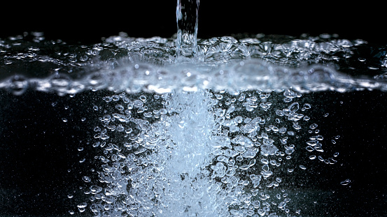 Close-up of water falling against black background.