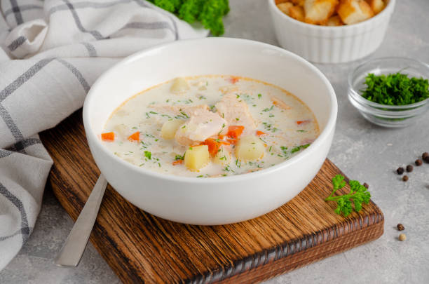 Salmon soup with cream, potatoes, carrots, herb and croutons in a bowl on a gray concrete background. Copy space. Salmon soup with cream, potatoes, carrots, herb and croutons in a bowl on a gray concrete background. Copy space Chowder stock pictures, royalty-free photos & images