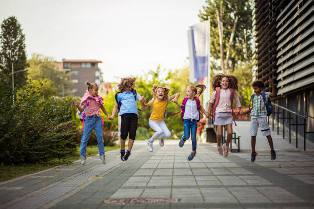 istock Group of elementary age schoolchildren jumping in schoolyard. 1312436299