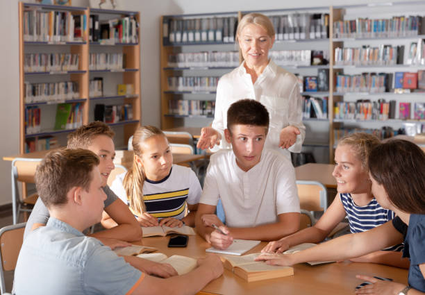 istock Group of nice schoolers discussing with teacher 1312439256