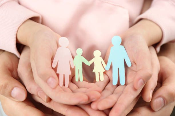 Parents and kid holding paper cutout of family in hands, closeup Parents and kid holding paper cutout of family in hands, closeup foster care stock pictures, royalty-free photos & images