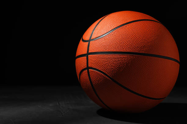 istock Basketball ball on grey stone table against dark background, space for text 1312439916