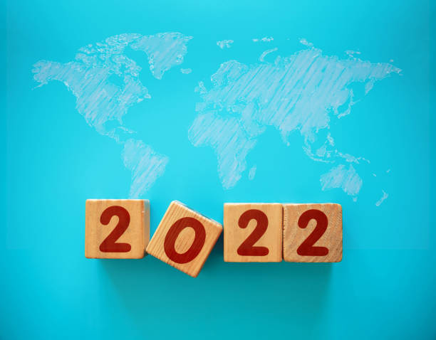 木ブロックと世界地図の背景を持つ新年2022