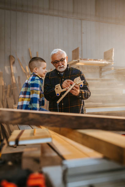istock Boy and his grandfather in carpenter workshop 1312443036