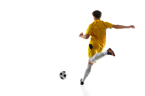 Back view. Young Caucasian man, male soccer football player in yellow uniform training isolated on white background. Concept of action, team sport game, energy, vitality. Copy space for ad.