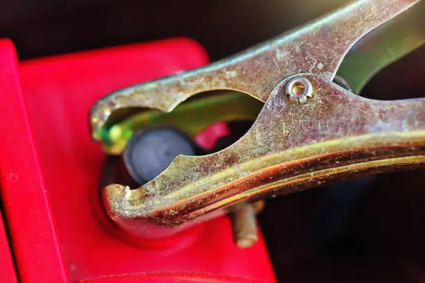 Photo of Close-up of a jumper cable clamped to the negative terminal of a car battery, providing starting assistance