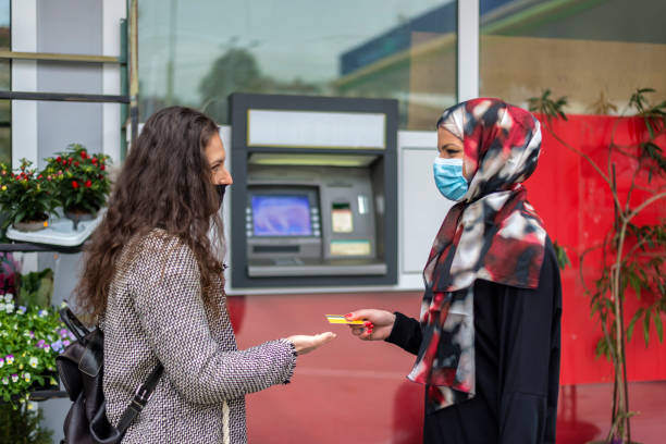 istock Two girlfriends with different religions in front of an ATM. 1312447183