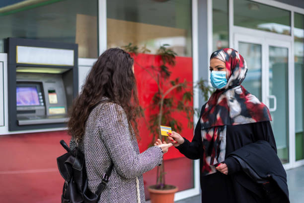 istock Two girlfriends with different religions in front of an ATM. 1312447184