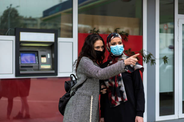 istock Two girlfriends with different religions in front of an ATM. 1312447201