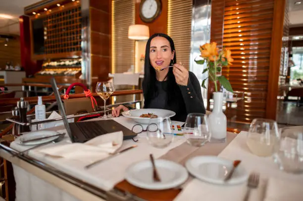 Beautiful businesswoman seen in a high end restaurant that she uses as a co-working office while having a fine-dining meal during a lunch break.