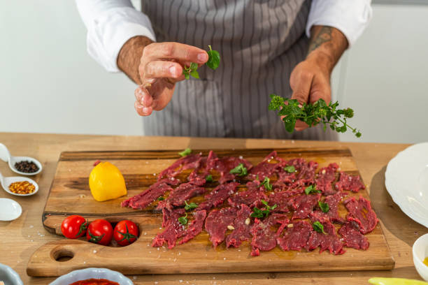 istock Close up of a chef adding basil to carpaccio meat 1312448703