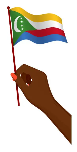 Vector illustration of Female hand gently holds small flag of Comoros islands. Holiday design element. Cartoon vector on white background