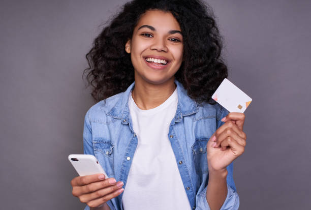 Young charming dark-skinned girl with a credit card and a smartphone. stock photo
