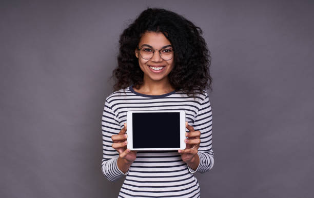 Smiling young afro girl with a tablet in her hands. stock photo