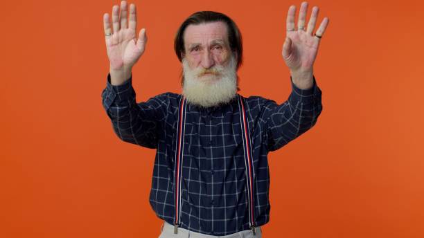 istock Happy friendly elderly man waves hand palm in hello gesture welcomes someone positive emotions 1312452884