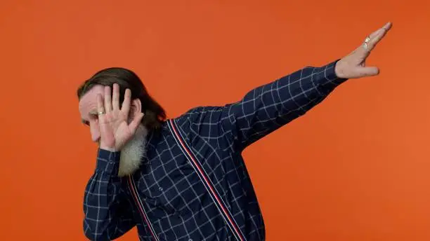 Photo of Trendy positive elderly man having fun dancing, dabbing raising hands, making dubdance gesture