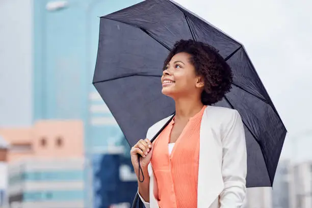 Photo of happy african american businesswoman with umbrella