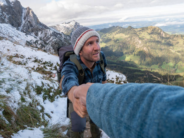 istock Hiker helping teammate to climb rock on mountain ridge 1312455236