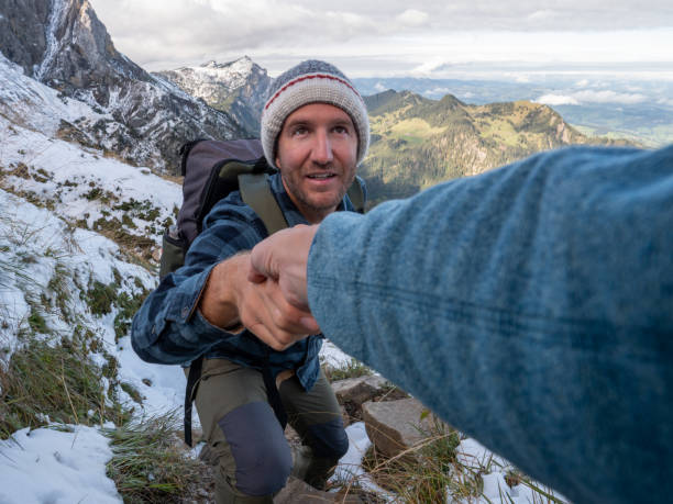 istock Hiker helping teammate to climb rock on mountain ridge 1312455265
