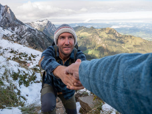istock Hiker helping teammate to climb rock on mountain ridge 1312455377