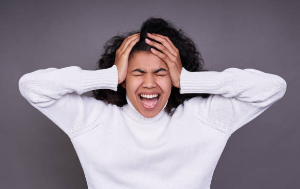 istock An African American screams, clutching her head in her temples with her hands. 1312456030