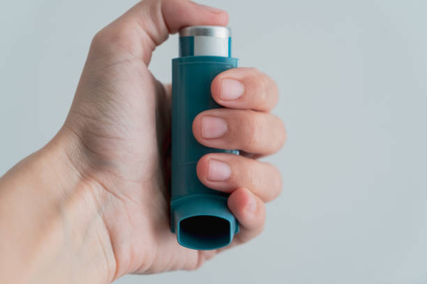 istock Human hand picking up an asthma inhaler 1312456301