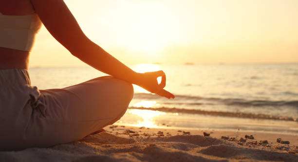 istock Faceless lady meditating in Lotus pose on beach 1312456353