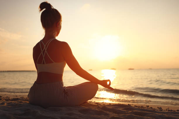 istock Calm woman meditating on beach at sunset 1312456423