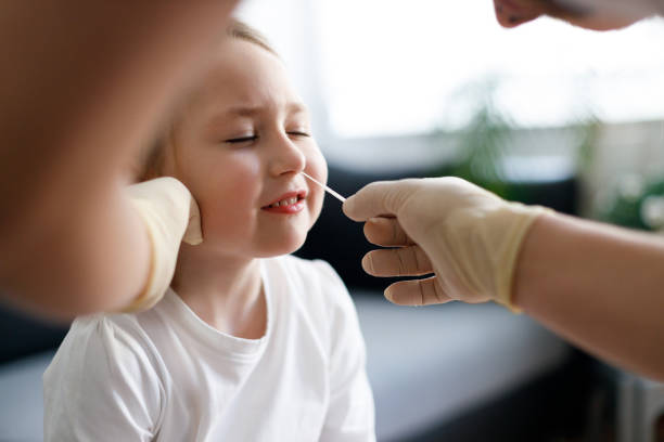 istock Doctor using cotton swab while testing little girl at rapid COVID-19 test at home 1312456643
