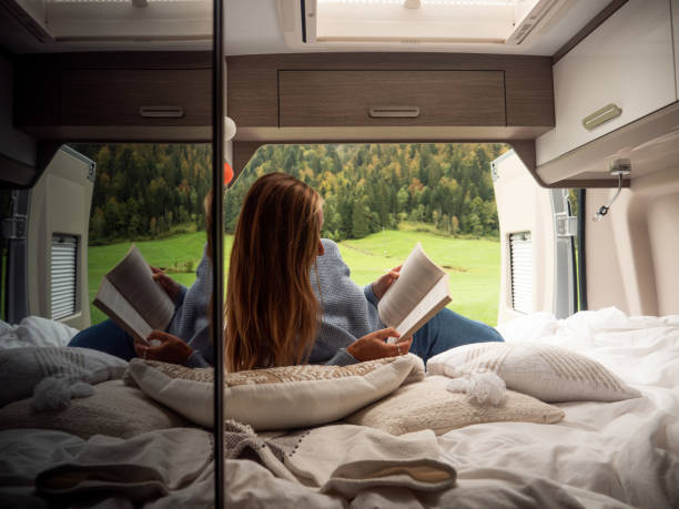 istock Serene woman reads her book inside a van overlooking alpine scenery 1312456821