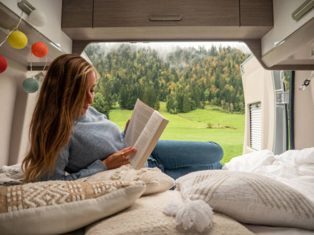 istock Serene woman reads her book inside a van overlooking alpine scenery 1312457519